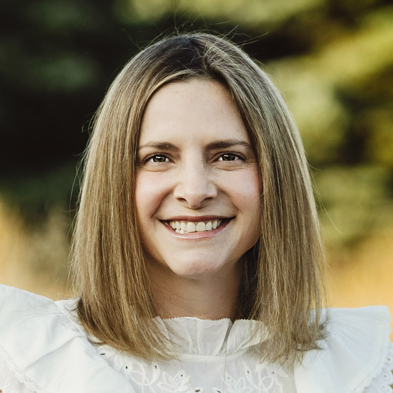 Headshot of Michaela Hackner, a white woman with blond hair wearing a white shirt.